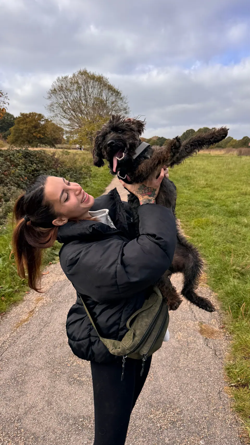 Erika lifting a small dog into the air on a country path
